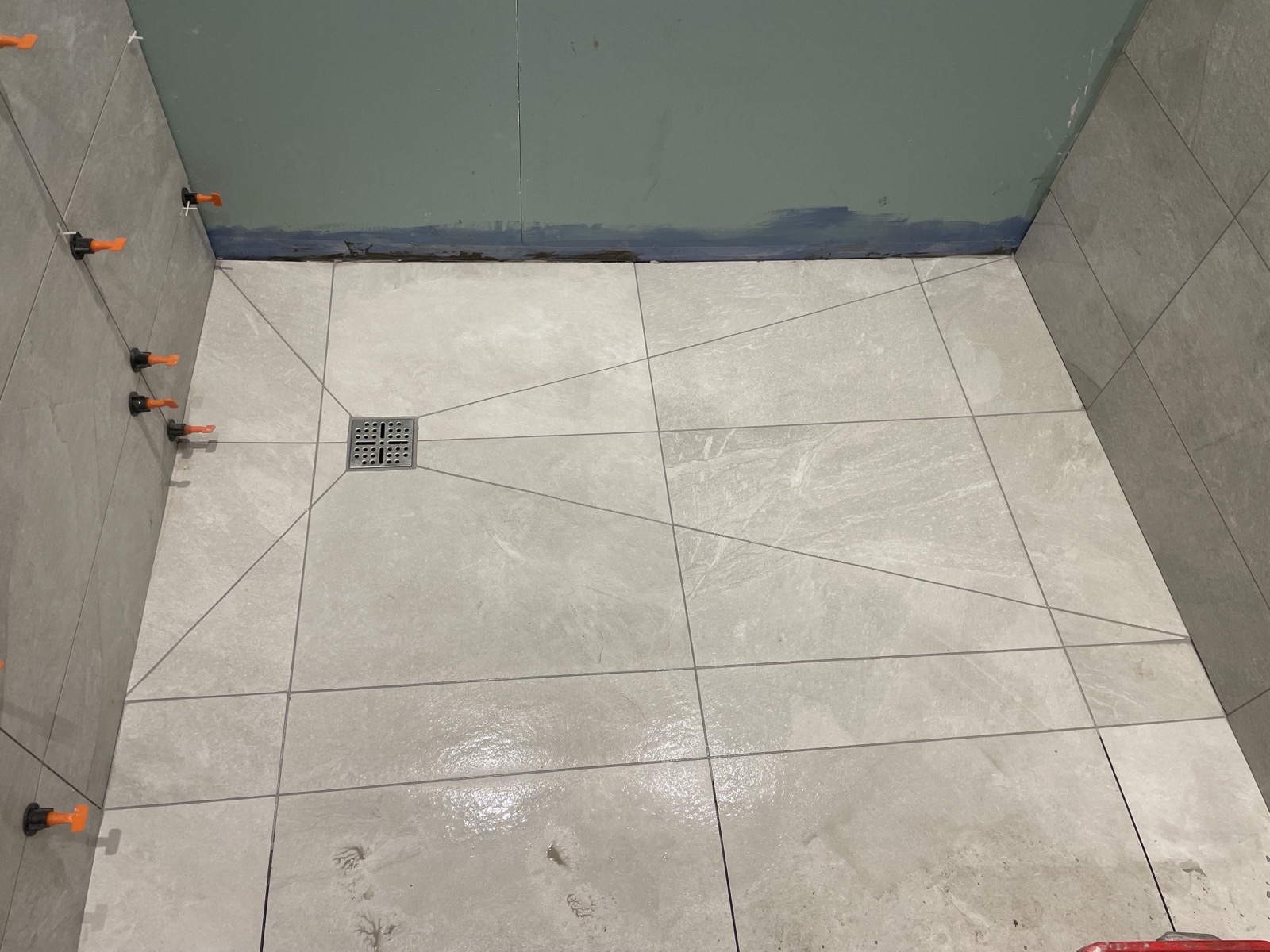 Herringbone tiled shower with black fittings and lit niche